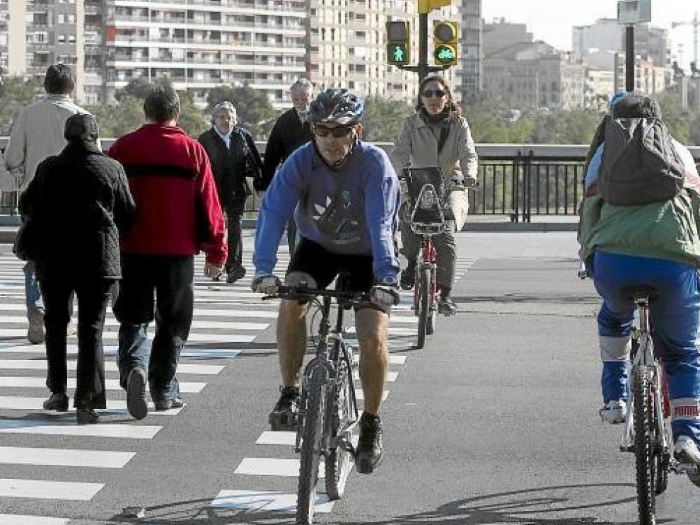 Varios ciclistas, en un paso de cebra con semáforo junto al puente de Santiago.