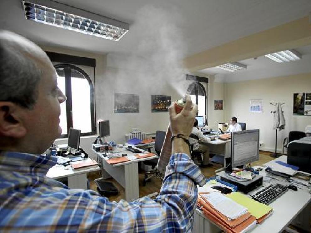 Un trabajador de los juzgados utiliza un ambientador para acabar con el mal olor de la oficina.