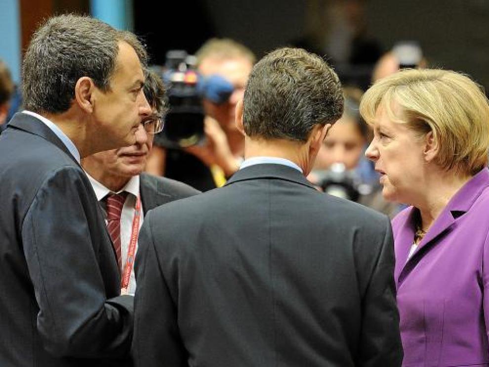 Zapatero conversa con Merkel y Sarkozy (de espaldas), ayer, en la cumbre de Bruselas.
