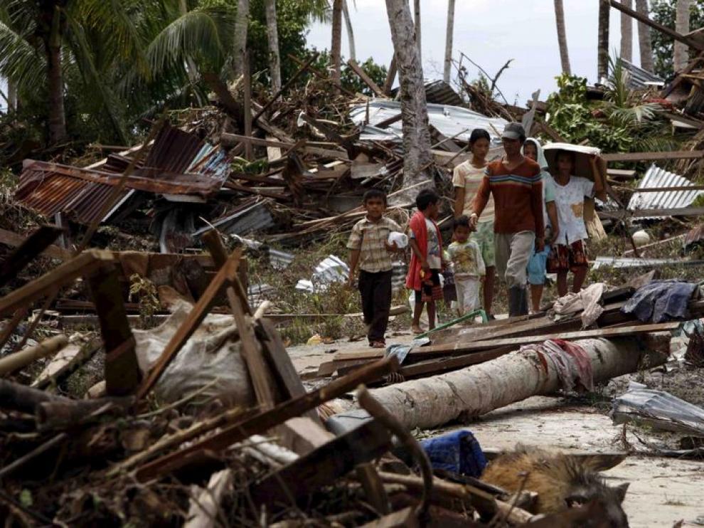 Una familia camina entre las ruinas provocadas por el tusnami en Pororogat, en las islas Metawai, al oeste de Sumatra