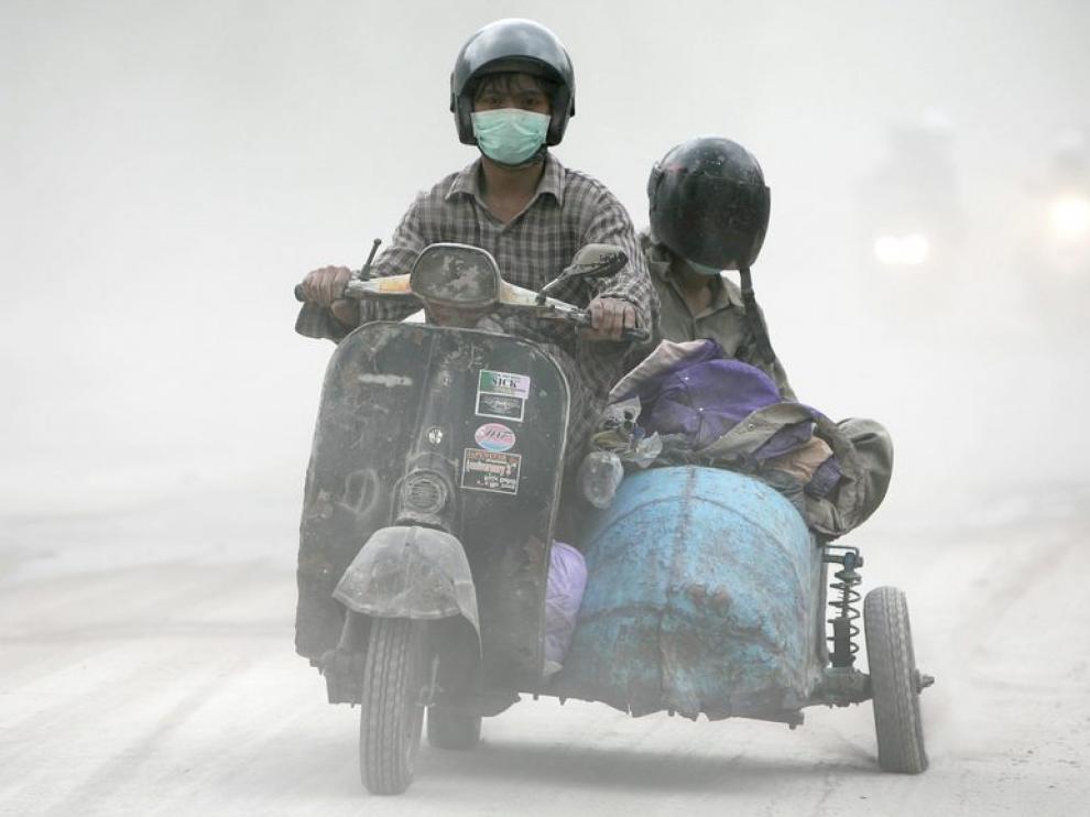 Dos hombres transitan en moto por una calle llena de ceniza en Yogyakarta