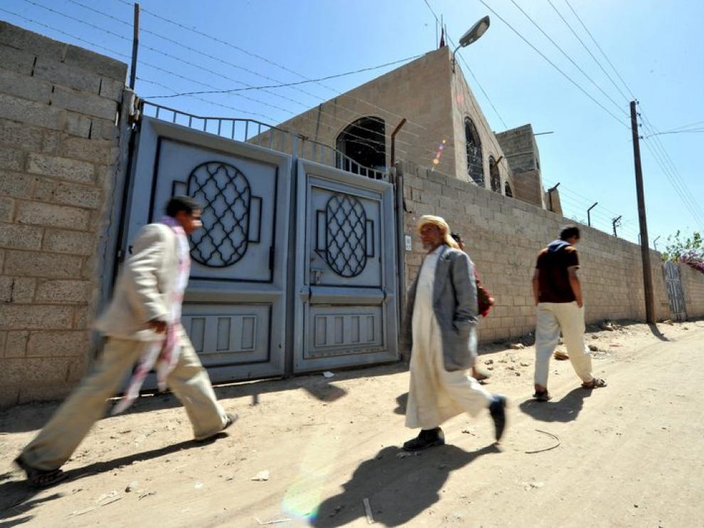 Transeúntes pasan junto a la casa donde vivía la estudiante detenida en Yemen por su relación con los explosivos