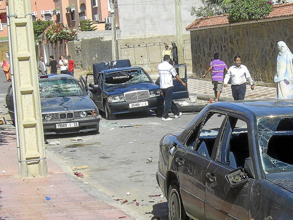 Varios saharauis observan tres coches con los cristales rotos, ayer en una calle de El Aaiún