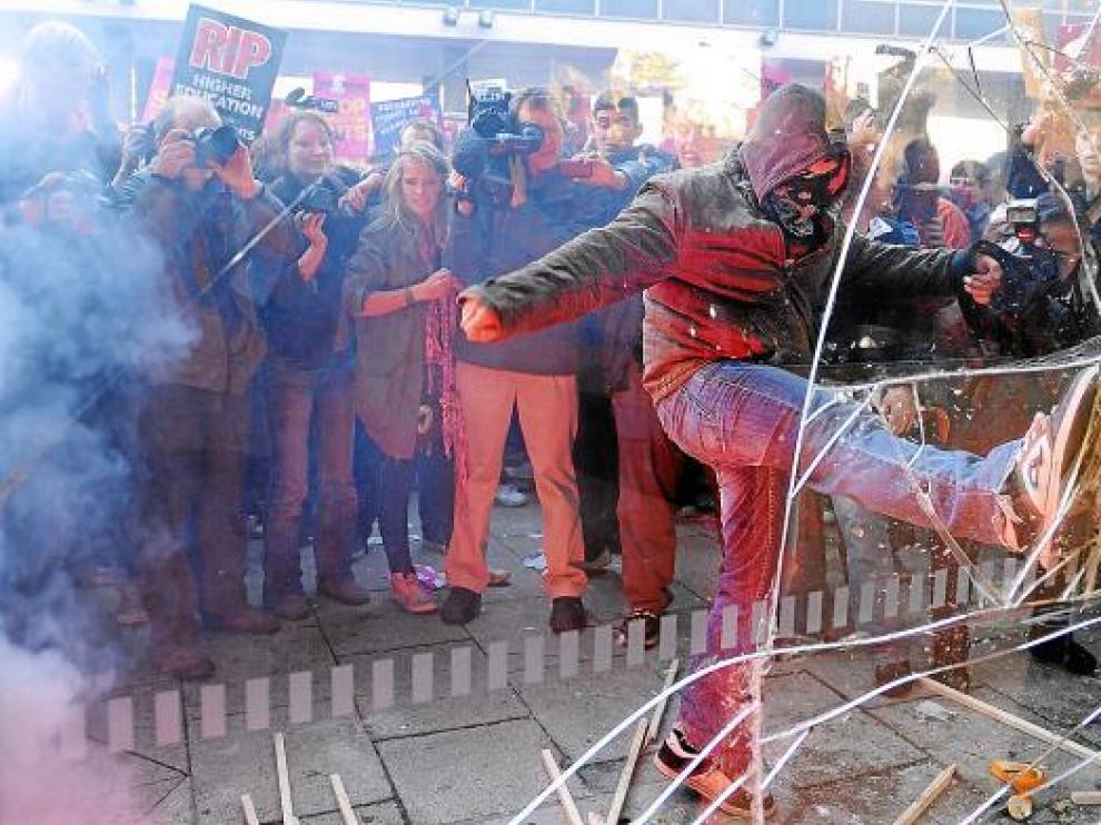 Uno de los manifestantes golpea con la pierna el cristal de la sede del partido.