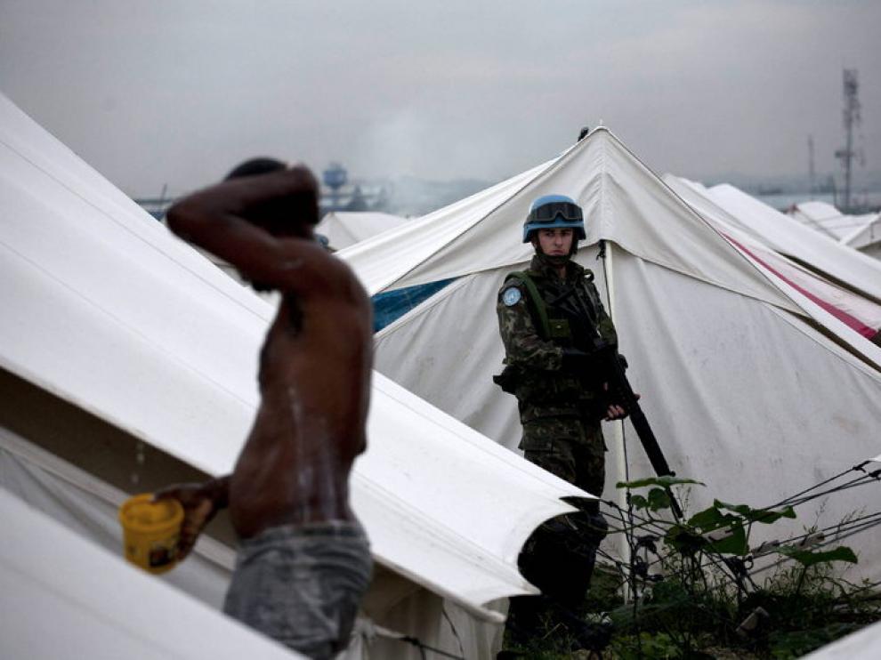 Un hombre se lava ante la atenta mirada de un soldado, ayer, en el campamento de Cite Soleil, Puerto Príncipe