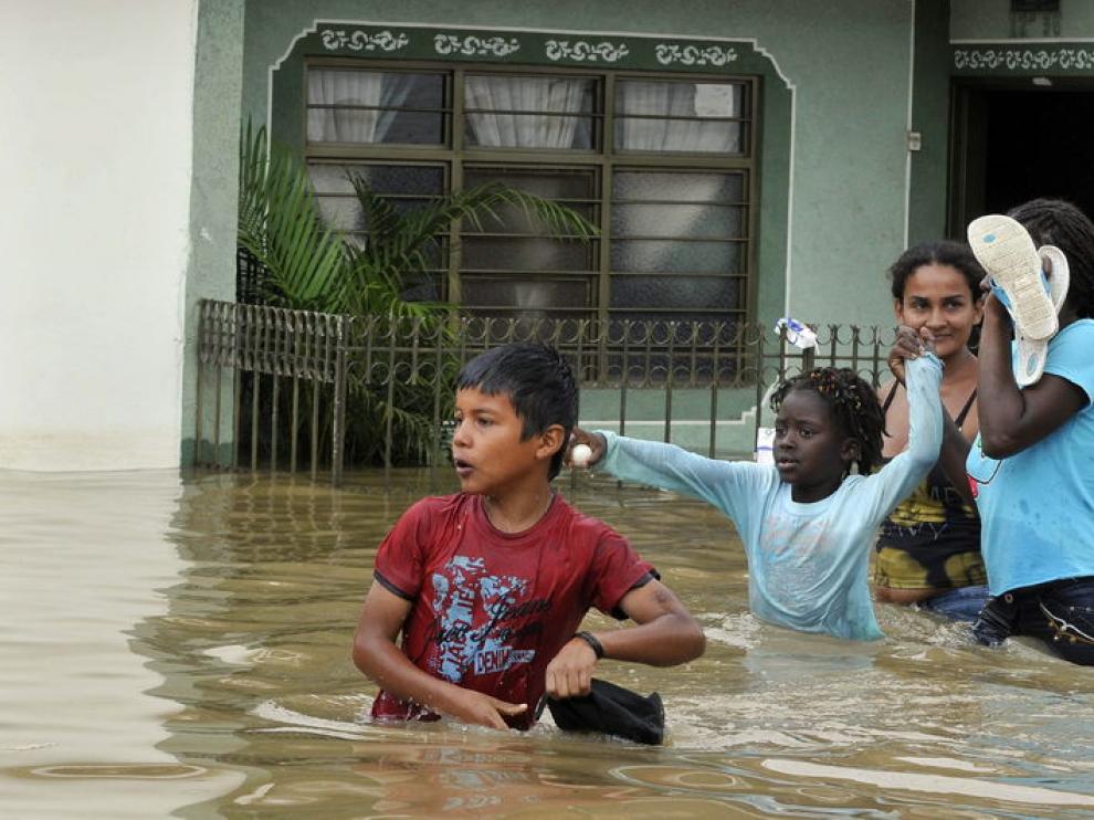 Unos niños intentan cruzar la calle inundada