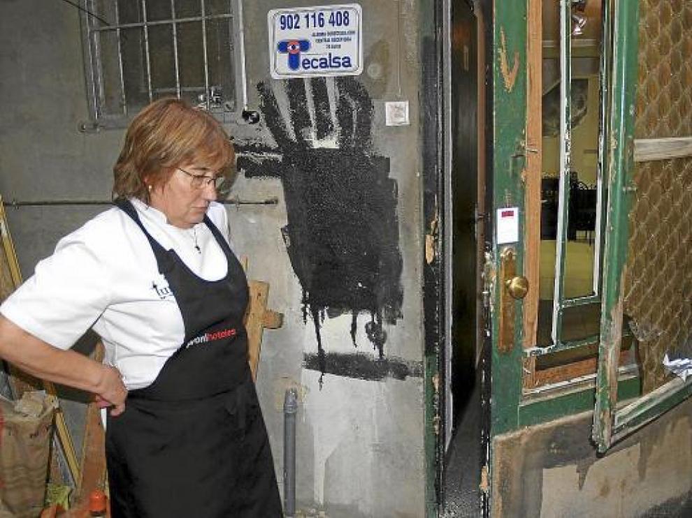 Lourdes Escartín, dueña del bar, observa los desperfectos en la puerta forzada por los cacos.