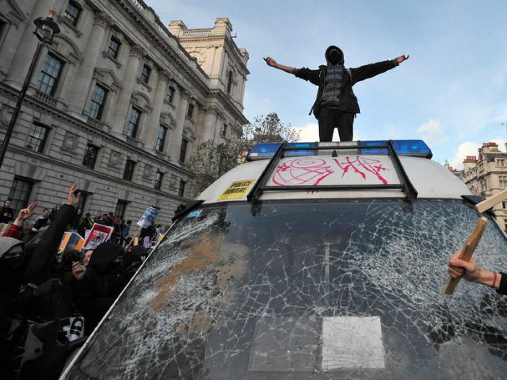 varios manifestantes destrozan un coche de policía.