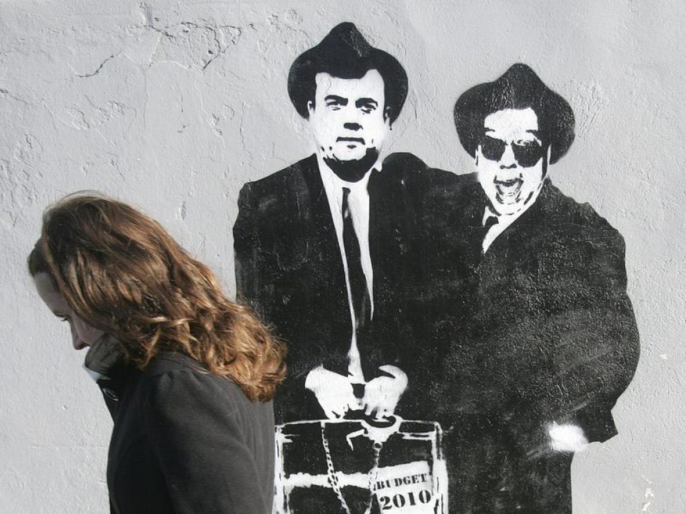 Una irlandesa pasa ante un mural que representa al primer ministro irlandes y al ministro de Finanzas