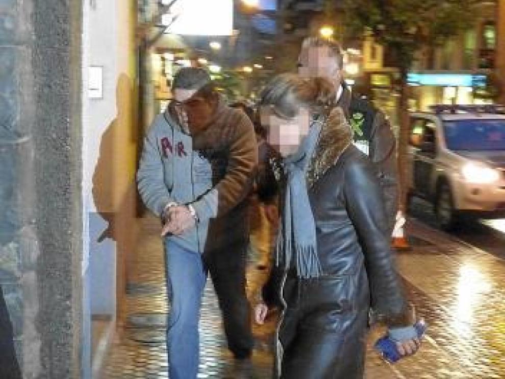 El detenido, esposado, a la entrada del domicilio.