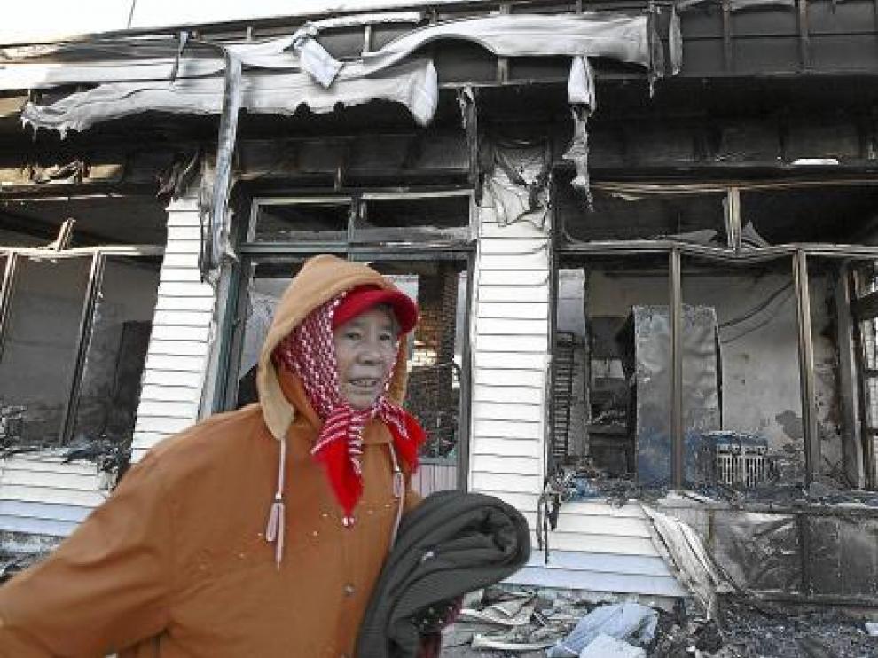 Una mujer pasa junto a una casa destruida en la isla surcoreana de Yeonpyeong, ayer.