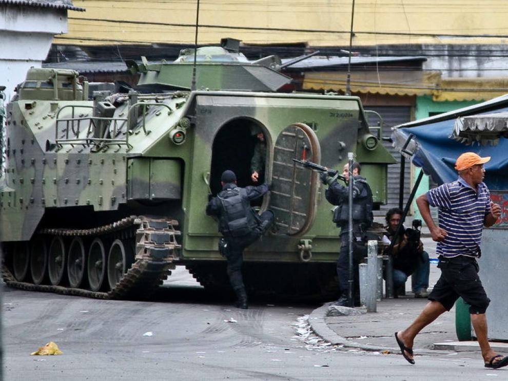 Varios policías prestan guardia junto a un vehículo de las Fuerzas Armadas en una de las zonas conflictivas de Río de Janeiro