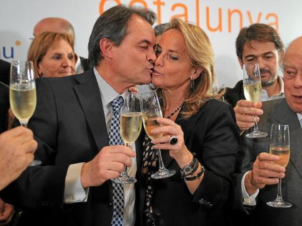 Artur Mas besa a su esposa en presencia de Jordi Pujol en la celebración del triunfo electoral.