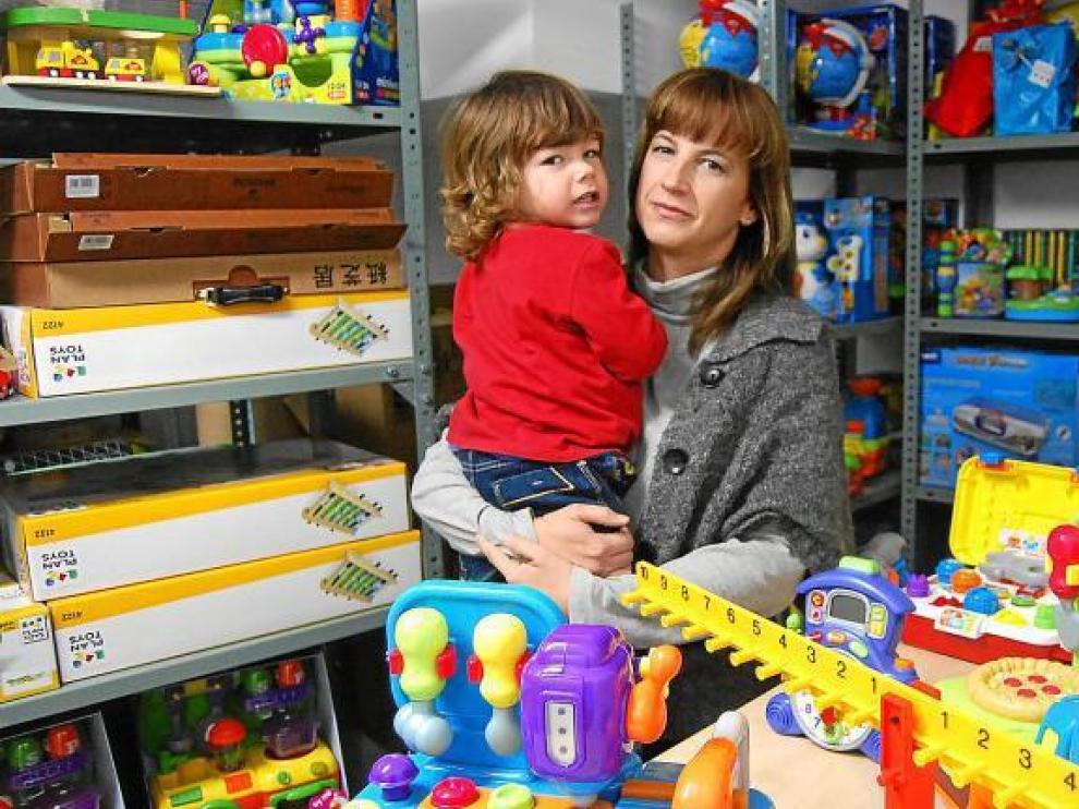 Magda, con su hijo pequeño en brazos, y rodeada de los cientos de juguetes que ofrece a través de su empresa de alquiler.