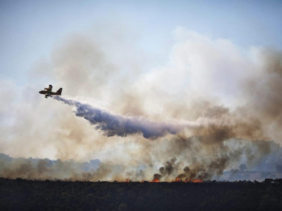 Un avión cisterna lanza agua para combatir el fuego en el bosque de Carmel