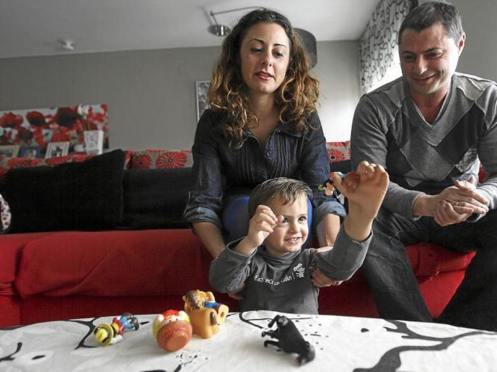 Javier coge un muñeco con su nueva mano bajo la atenta mirada de sus padres, Alicia Orce y Rubén Gimeno.