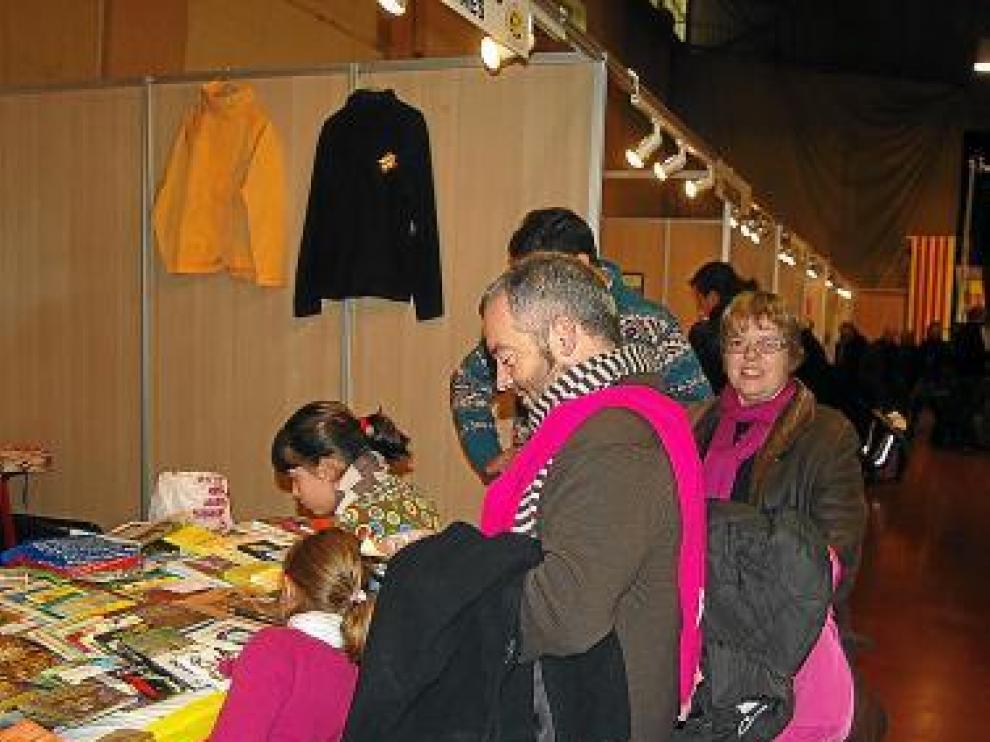Niños y adultos consultan los títulos de uno de los expositores.