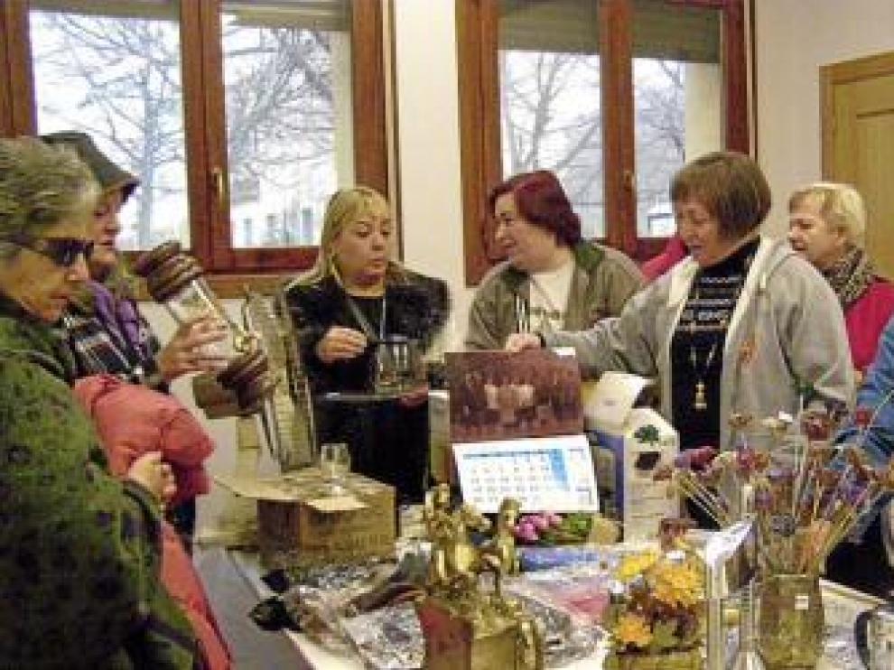 Varias mujeres ojean los objetos a la venta en el rastrillo.