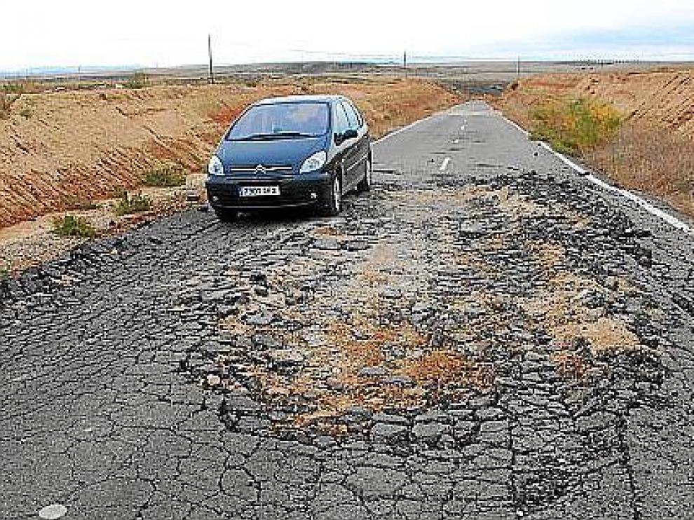 Un turismo trata de sortear un gran socavón que ocupa casi todo el ancho de la carretera.