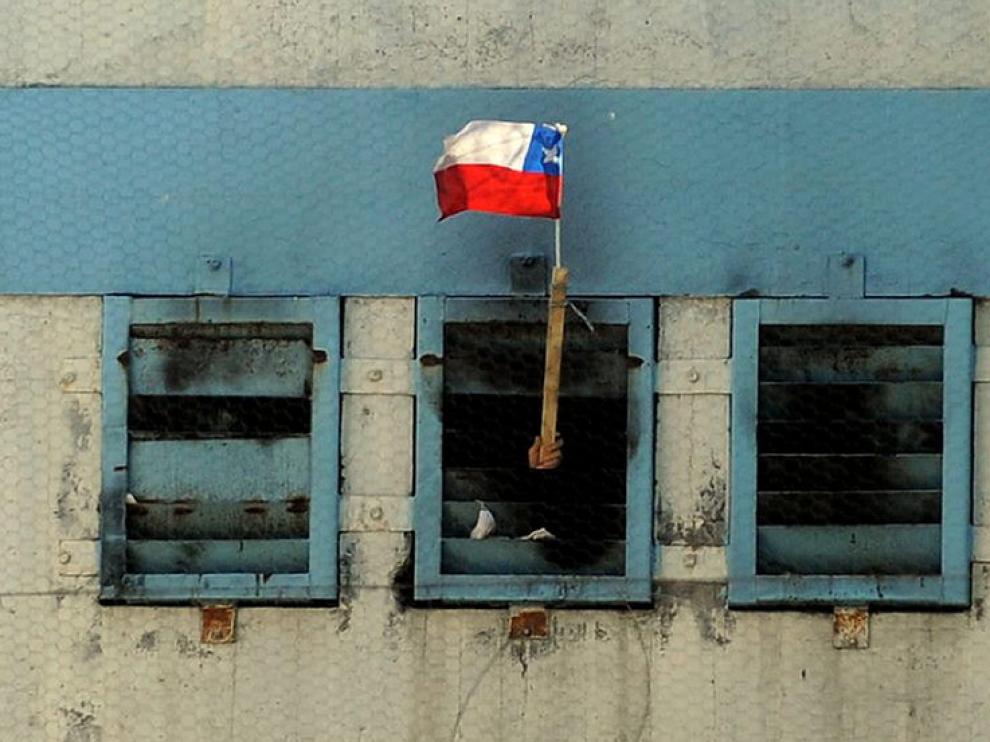 Un interno muestra una bandera chilena desde el interior de la cárcel.