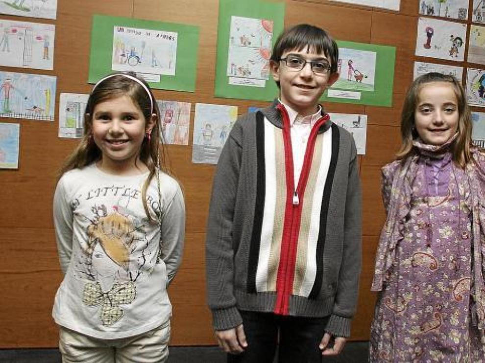 Los tres niños premiados posan delante de sus dibujos, con los que ilustran la igualdad.