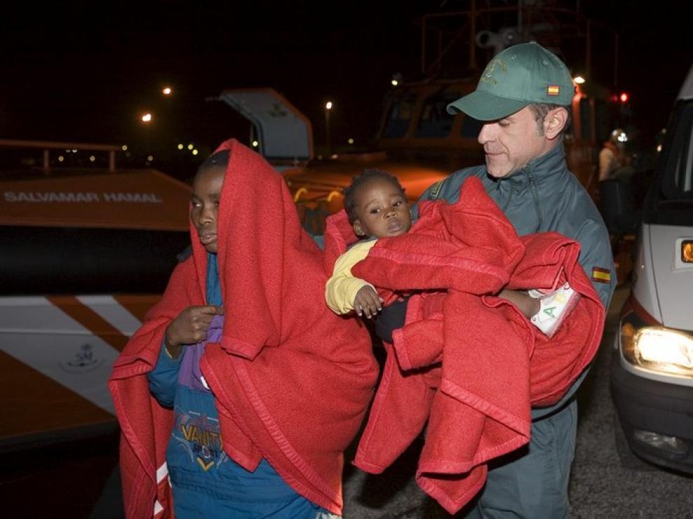 Un miembro de la Guardia Civil ayuda a dos de los treinta inmigrantes.
