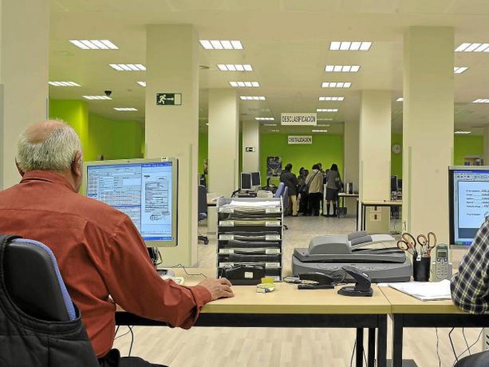 Ángel Nadal y Carlos Mateo (los dos de espaldas) son dos de los trabajadores del centro de digitalización del Grupo DFA en Zaragoza.