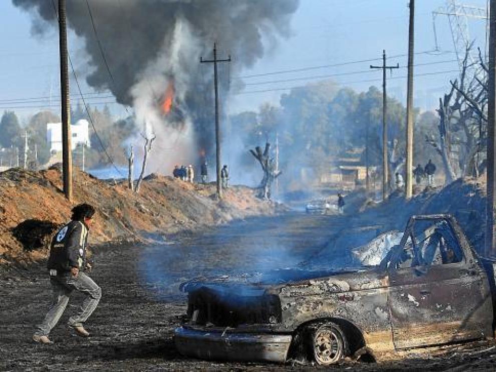 Algunos vecinos observan camiones incendiados tras la explosión en San Martín Texmelucan.
