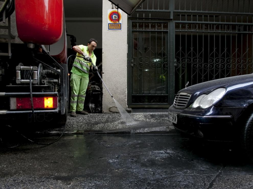 Un trabajador municipal limpia los restos del incendio de un contenedor de basuras