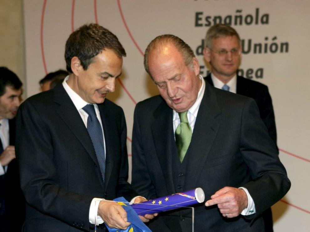 El presidente del Gobierno, Jose Luís Rodríguez Zapatero muestra al rey el distintivo que acredita a España en la presidencia de la UE