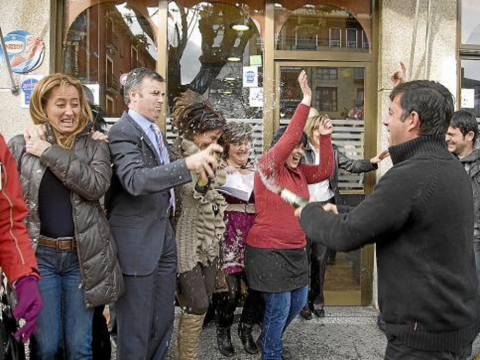 El propietario del bar Rioja, situado junto a la peluquería, riega de champán a varias personas.
