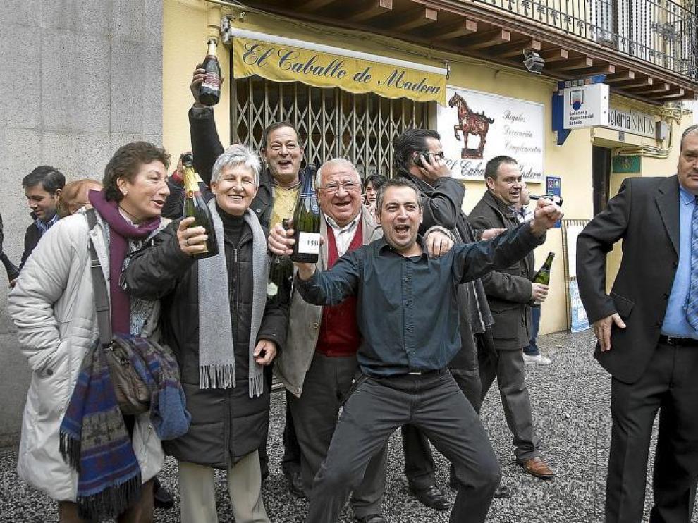 El peluquero José Luis Vicén (en el centro) celebra el premio con una botella en la mano y acompañado de varios afortunados.