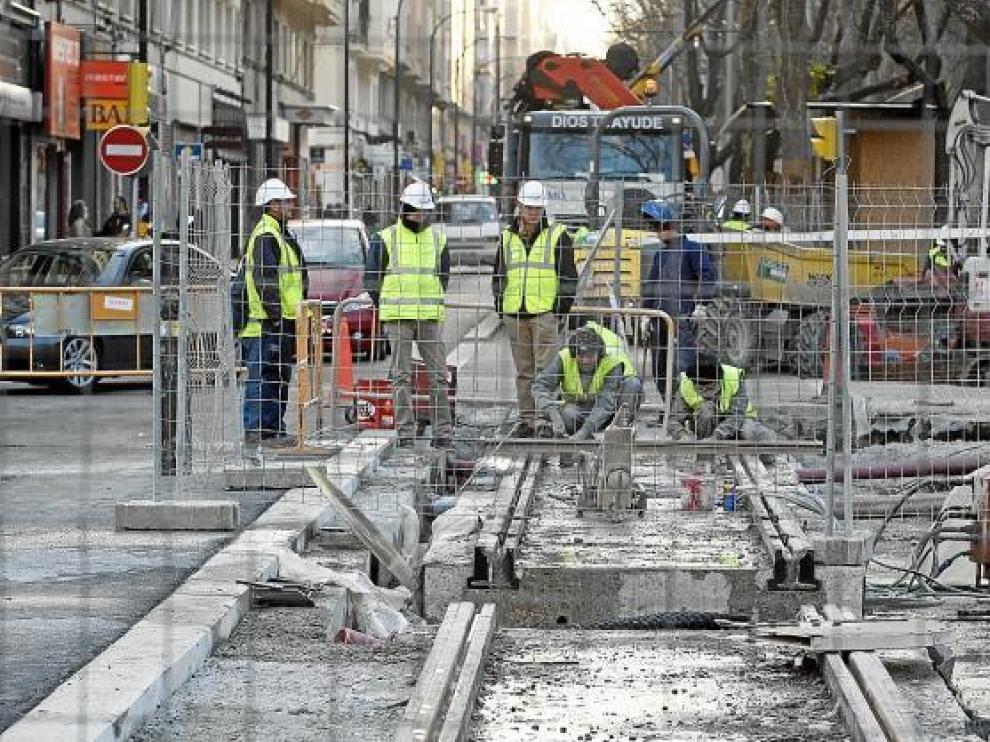 Varios operarios contemplan los trabajos, con un tramo de carril retirado en primer término.