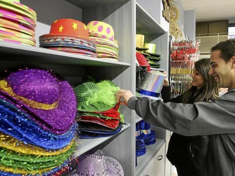 Dos jóvenes eligen gorros, dentro de la amplia gama de artículos que hay para los cotillones.