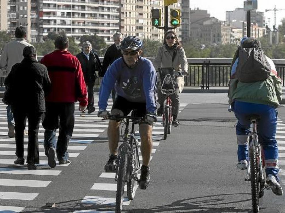 Tres ciclistas en un paso regulado por semáforos junto al puente de Santiago.