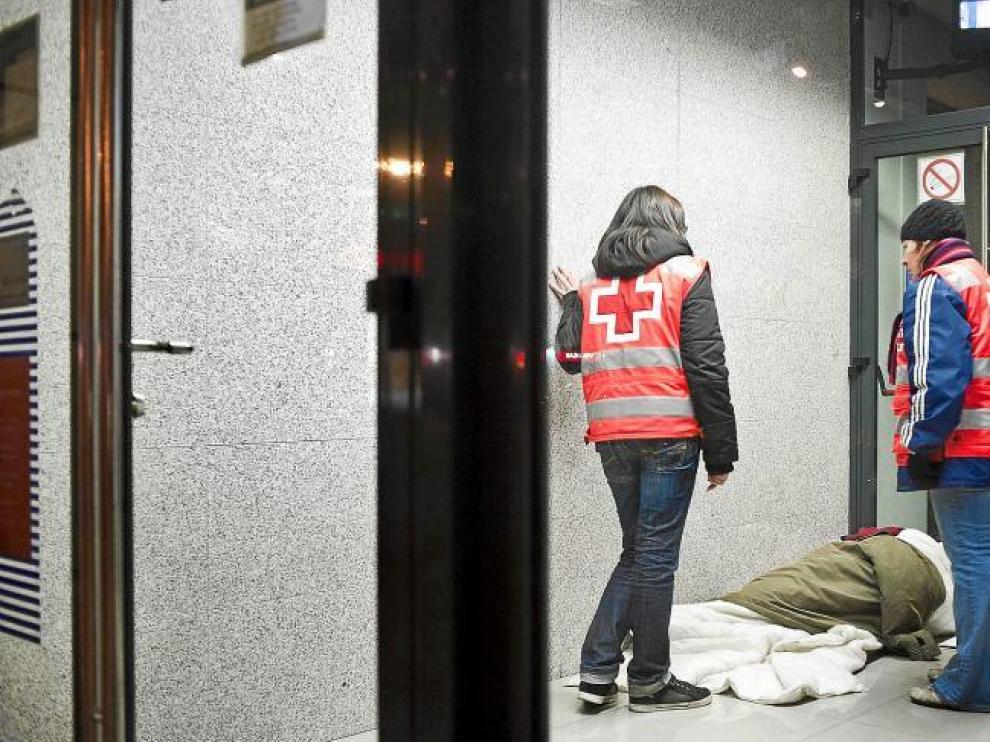 Dos voluntarios de Cruz Roja atienden a una persona sin hogar en Zaragoza.