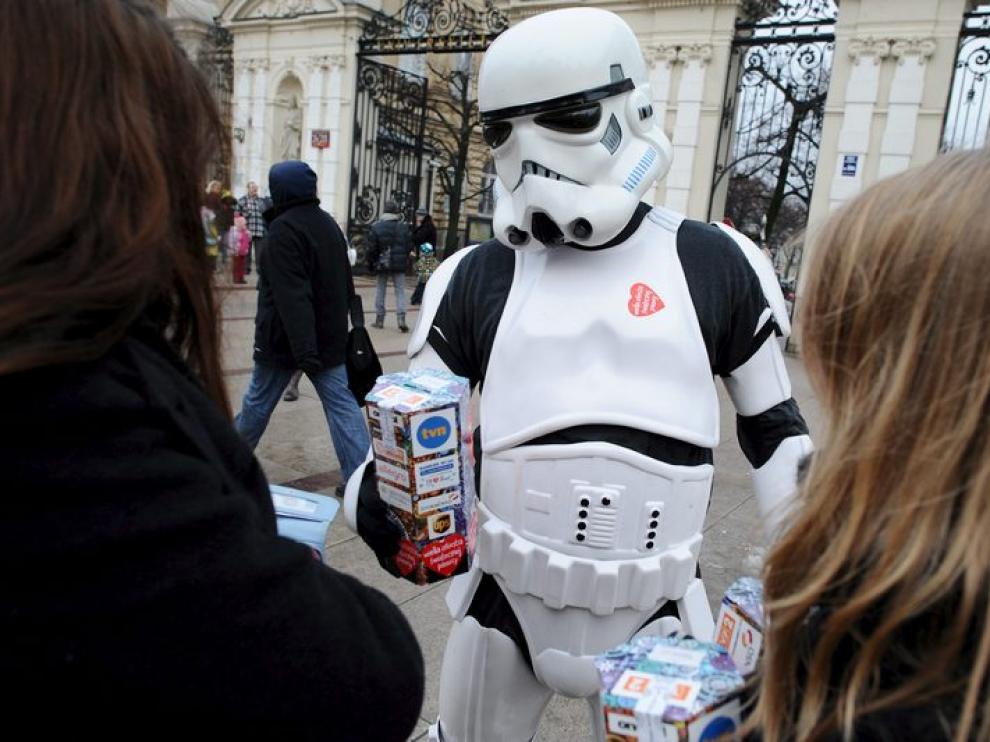 Dos jóvenes se acercan a un voluntario disfrazado de personaje de 'Star Wars' para realizar su donación