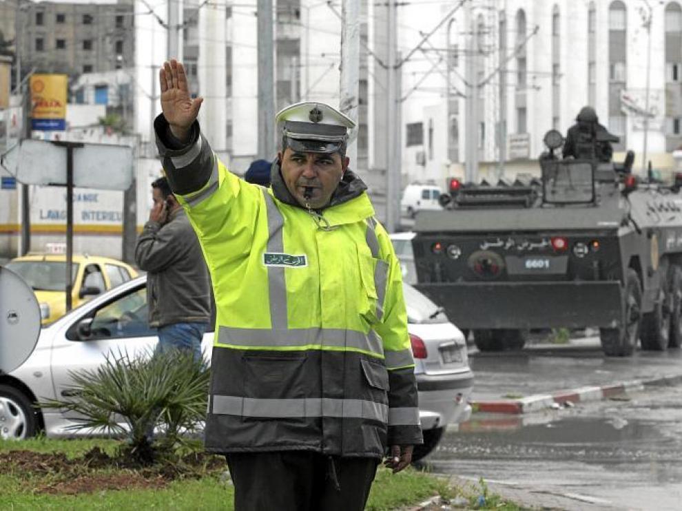 Un agente regula el tráfico en la capital tunecina ante una de las tanquetas que tomaron ayer las calles de la ciudad.