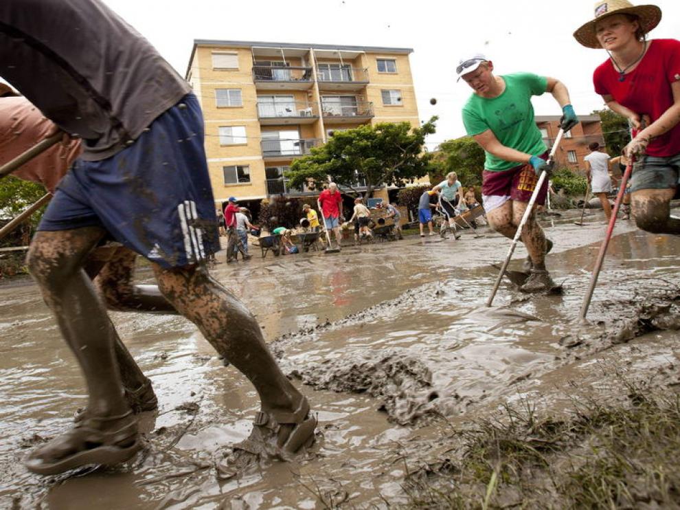 Varios ciudadanos retiran el lodo de las calles de la ciudad
