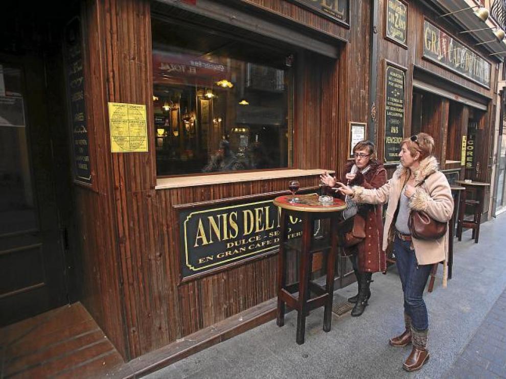Dos clientes utilizan las mesas colocadas a las puertas de una céntrica cafetería para tomar una consumición sin dejar de fumar.