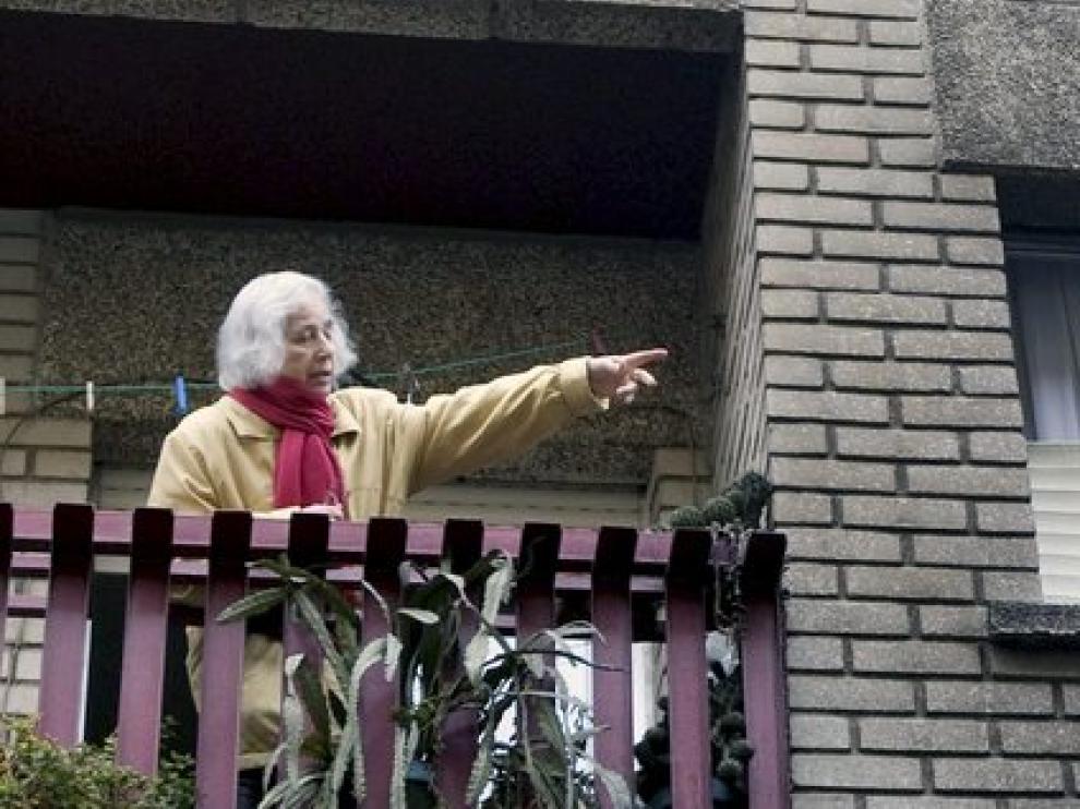 Una mujer señala la fachada ennegrecida de su casa por el fuego