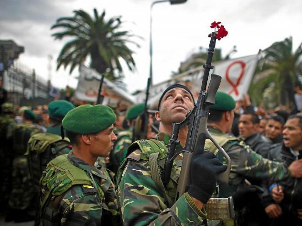 Un militar tunecino, con una flor en su arma, mira hacia el cielo durante la concentración ante la sede del partido RCD.