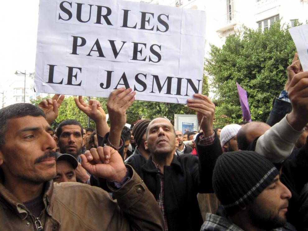Tunecinos se manifiestan con una pancarta que dice en francés "Encima de las piedras, hay un jazmín"