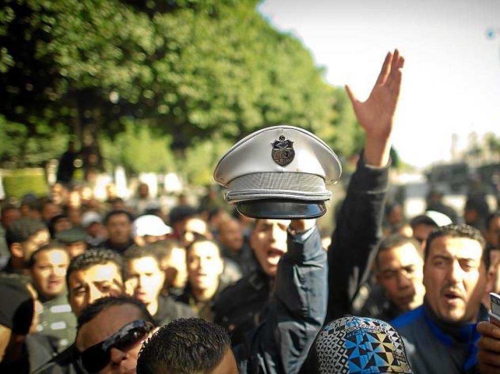 Un manifestante muestra un gorro de la Policía tunecina que ayer se unieron a las protestas.