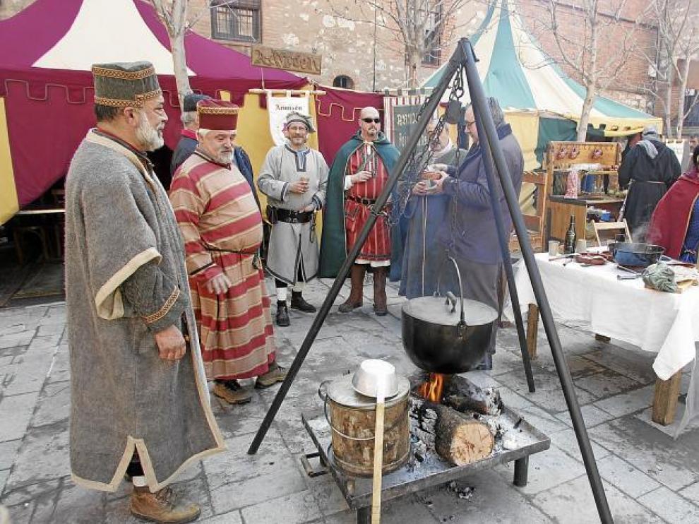 Miembros de uno de los grupos cocinando en la calle, con las jaimas al fondo, en la pasada edición de las Bodas de Isabel.
