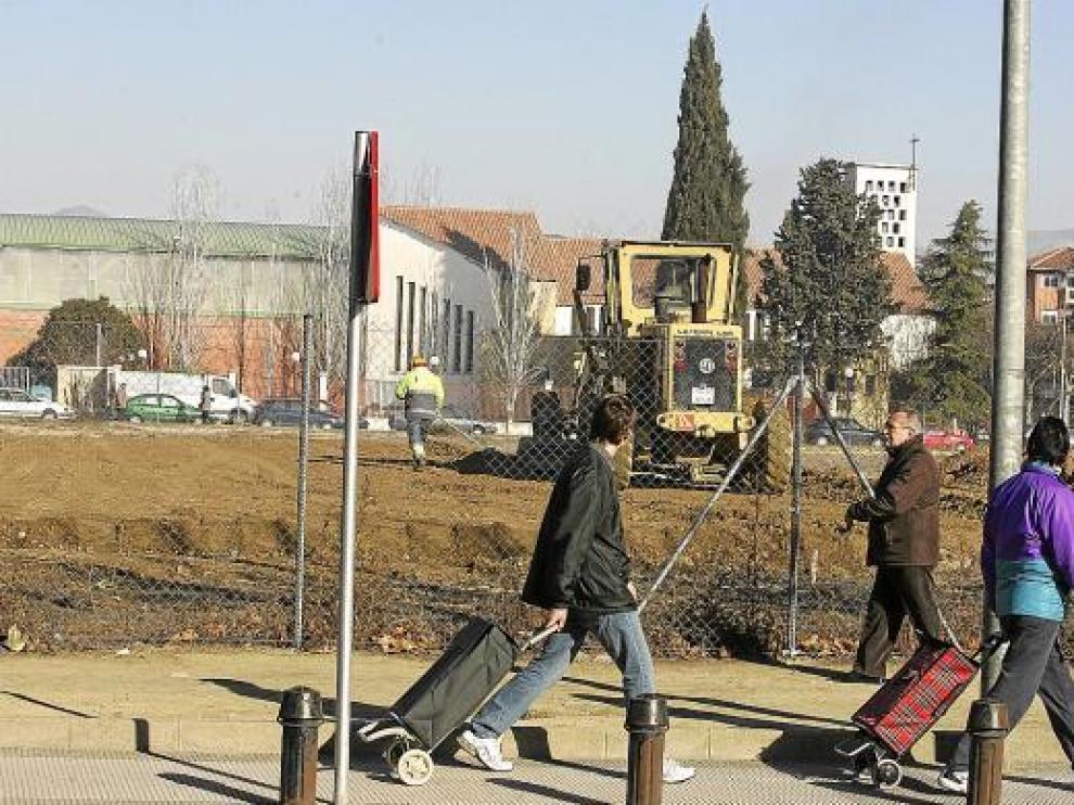Varios peatones observan las obras en el solar de la cárcel desde la calle Aragón.