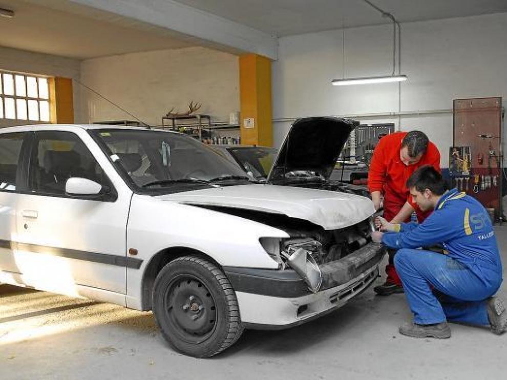 Dos mecánicos de Teruel reparaban ayer los daños de un coche que chocó con un jabalí.