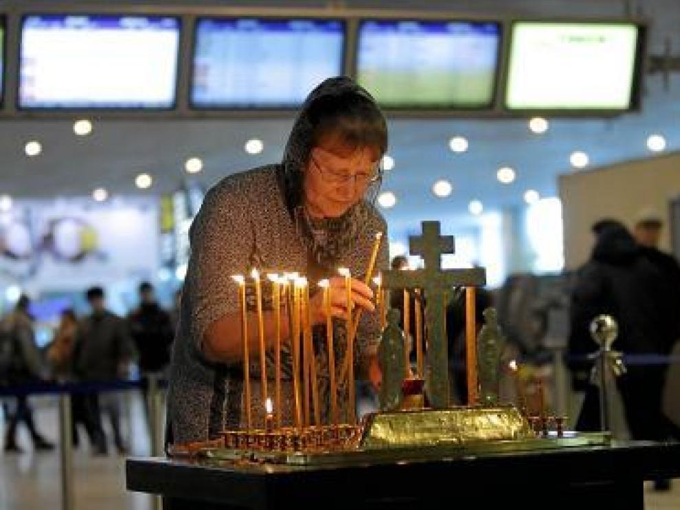 Una mujer enciende una vela, en el aeropuerto de Domodedovo.