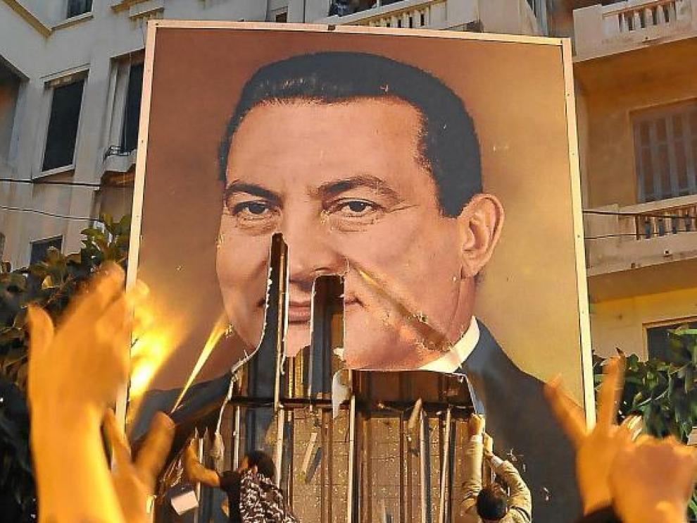 Dos egipcios rompen un cartel con la imagen de Mubarak, ayer en la ciudad de Alejandría.