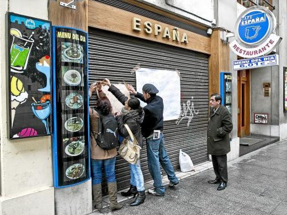 Algunos empleados colocaban ayer carteles reivindicativos en la puerta del bar España.